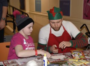 Sergeant Jean-Paul Trudeau makes crafts with a child at Sick Kids Hospital in Toronto during Operation Ho Ho Ho. PHOTO: © Steve Bigg, Locked On Photography