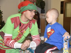 Corporal Jesse MacIlroy, an elf from 400 Tactical Helicopter Squadron, and a child at Sick Kids Hospital in Toronto share a conversation during Operation Ho Ho Ho. PHOTO: © Steve Bigg, Locked On Photography
