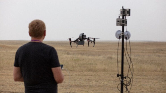 A man flies a drone aircraft over an open field.