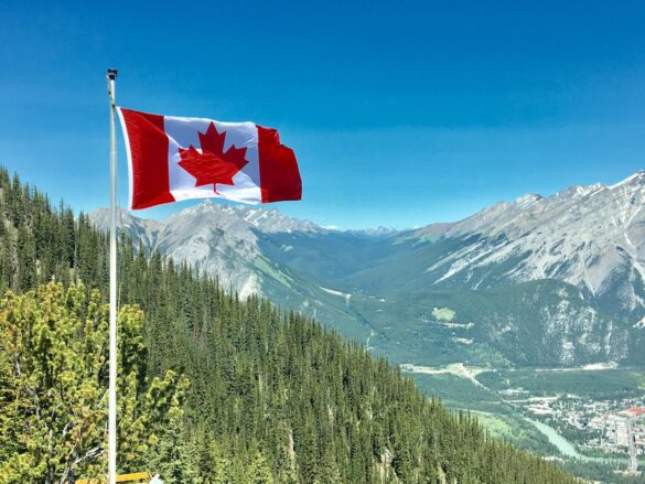 Canadian flag flying over a range of mountains.