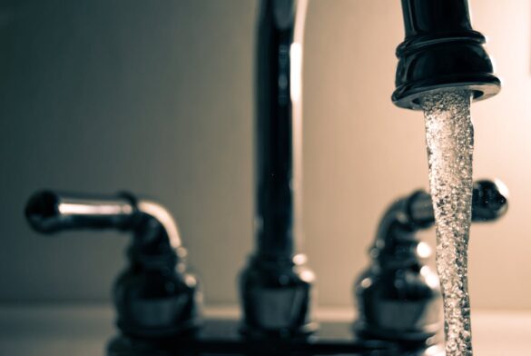 Clean, clear water pours out of a kitchen faucet.