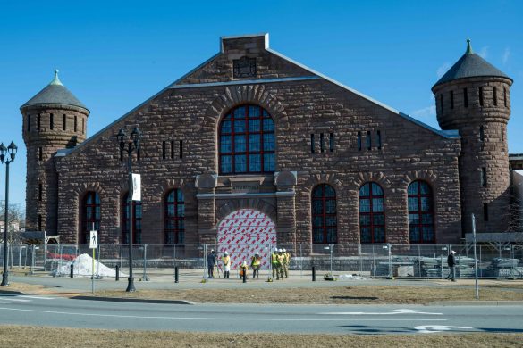 A front view of The Halifax Armoury, where a group of construction workers are gathered near the entrance.