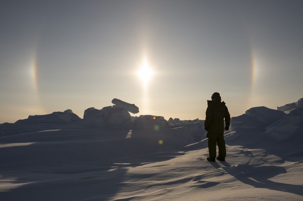 A sundog appears over Pioneer Bay, NU while Major Shawn Dumbreck, Officer in Command of the Canadian Armed Forces' Arctic Response Company Group (ARCG), conducts a reconnaissance of Objective EIDER as part of Operation NANOOK-NUNALIVUT on March 24, 2019. Photo: Avr Jérôme J.X. Lessard NK06-2019-0007-001 ~ Un faux soleil apparaît au-dessus de la baie Pioneer, au Nunavut, au même moment oà¹ le major Shawn Dumbreck, commandant du Groupe-compagnie d'intervention dans l'Arctique (GCIA) des Forces armées canadiennes, mène une reconnaissance de l'objectif EIDER dans le cadre de l'opération NANOOK-NUNALIVUT, le 24 mars 2019. Photo : Avr Jérôme J.X. Lessard NK06-2019-0007-001
